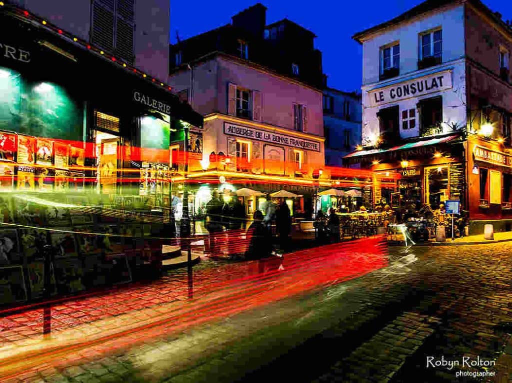Charming Parisian street at night with cafes and cobblestones.